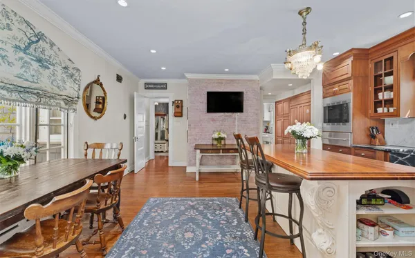 a kitchen with stainless steel appliances kitchen island granite countertop a refrigerator a stove top oven and a dining table with wooden floor