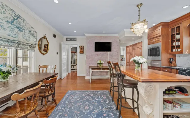 a kitchen with stainless steel appliances kitchen island granite countertop a refrigerator a stove top oven and a dining table with wooden floor