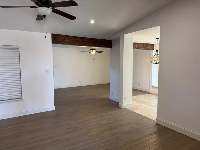 an empty room with wooden floor a ceiling fan and a window