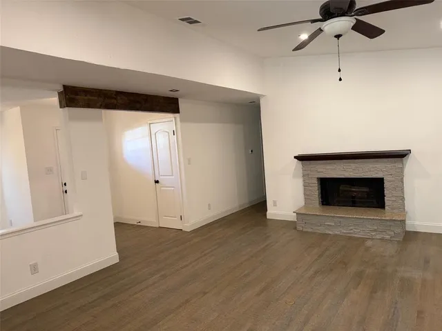 an empty room with wooden floor a fireplace and windows