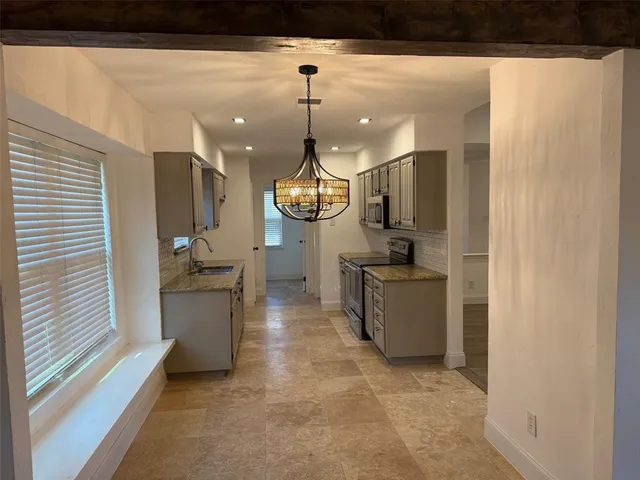 a room with kitchen island stainless steel appliances a stove a sink and a window