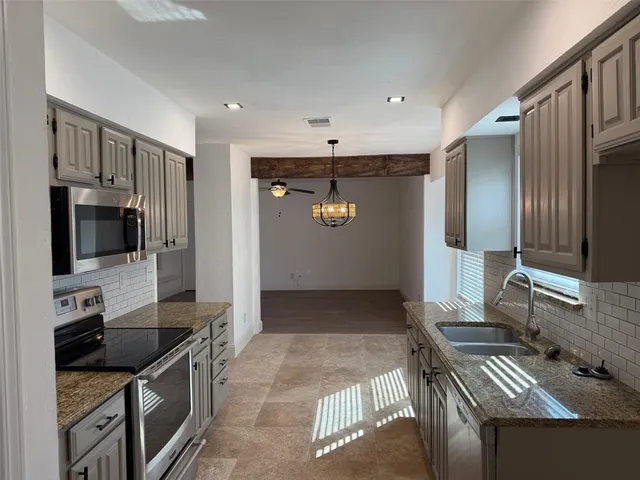a kitchen with stainless steel appliances granite countertop a refrigerator and a stove top oven