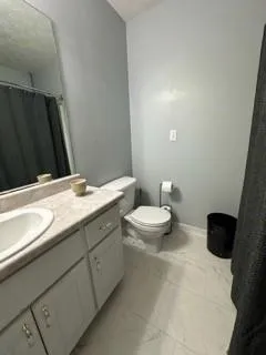 a bathroom with a granite countertop sink a toilet and a mirror