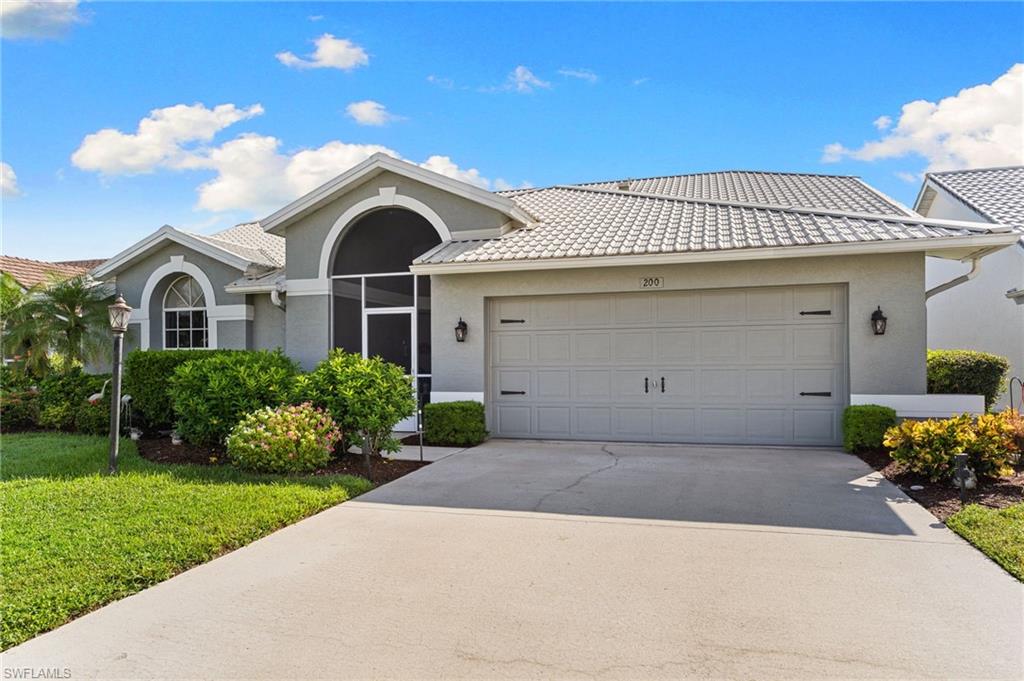 200 St James Way Naples, FL 34104 - Photo 2 of 45 Ranch-style house featuring stucco siding, driveway, an attached garage, a front yard, and a METAL roof