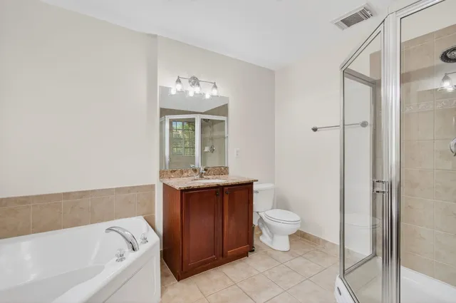 a bathroom with a granite countertop bathtub shower sink vanity and toilet