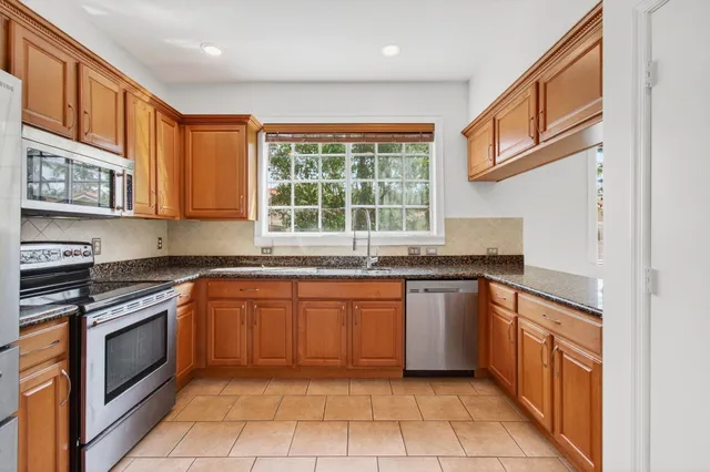 a kitchen with granite countertop stainless steel appliances a sink stove and a refrigerator