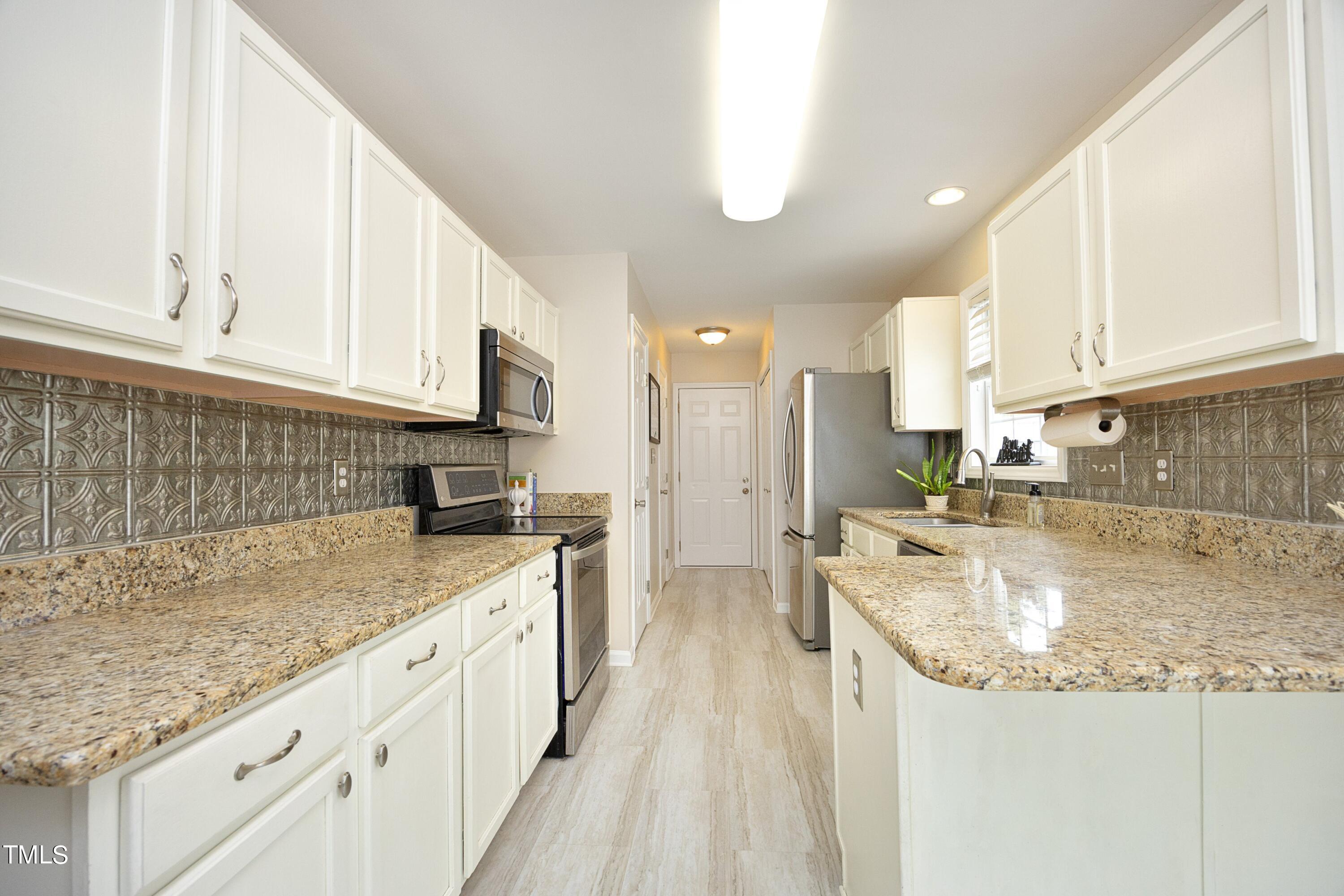 8904 Castleton Lane Raleigh, NC 27615 - Photo 15 of 43 a kitchen with granite countertop a sink a counter top space stainless steel appliances and cabinets
