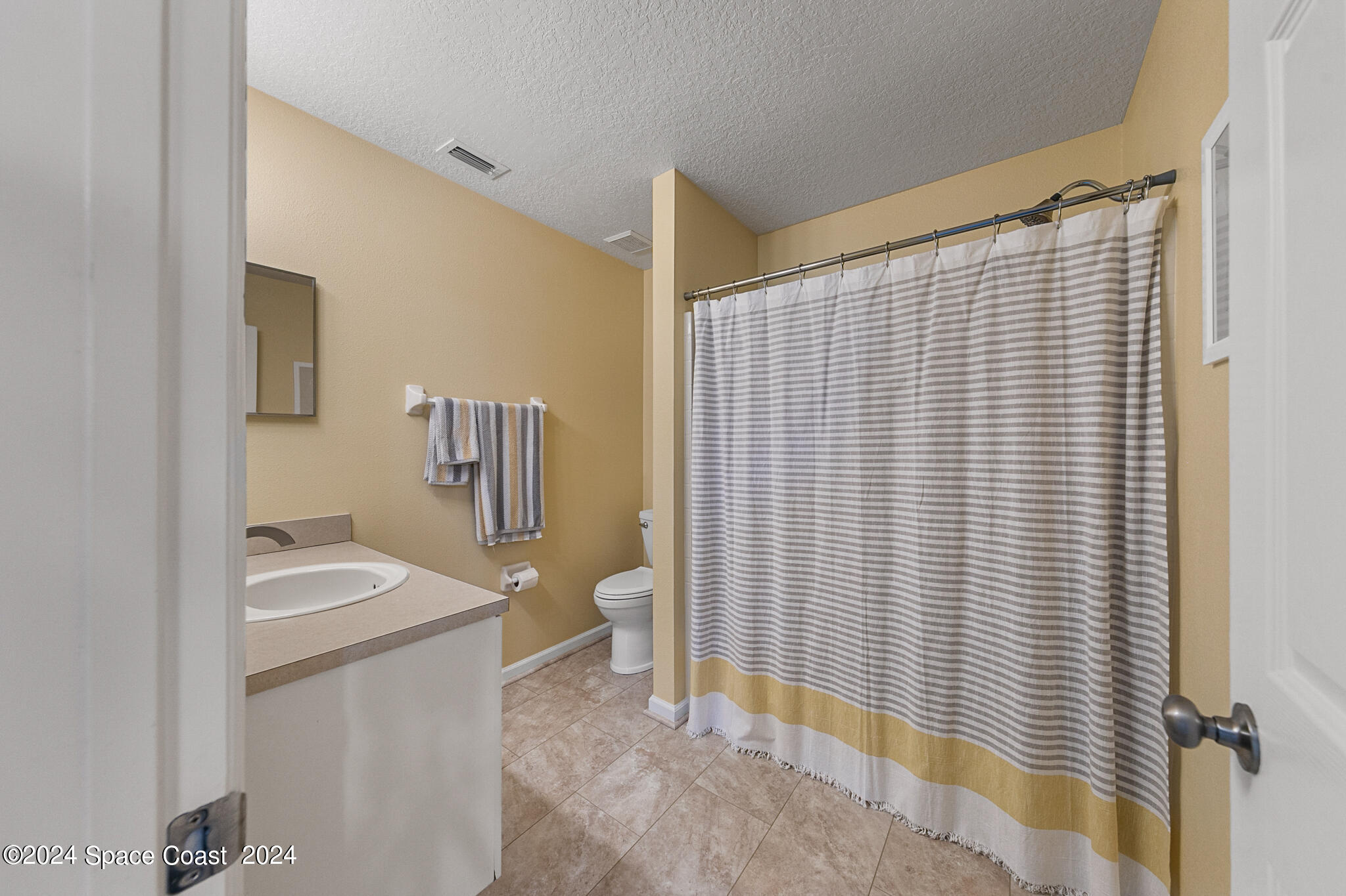 890 Luminary Circle, Unit 103 Melbourne, FL 32901 - Photo 20 of 32 a bathroom with a sink a toilet and shower curtain