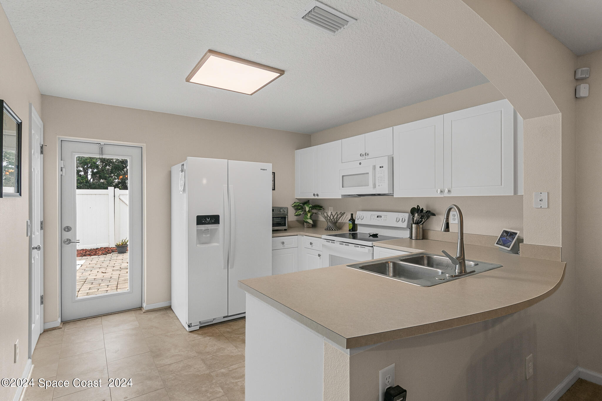 890 Luminary Circle, Unit 103 Melbourne, FL 32901 - Photo 9 of 32 a kitchen with white cabinets and refrigerator