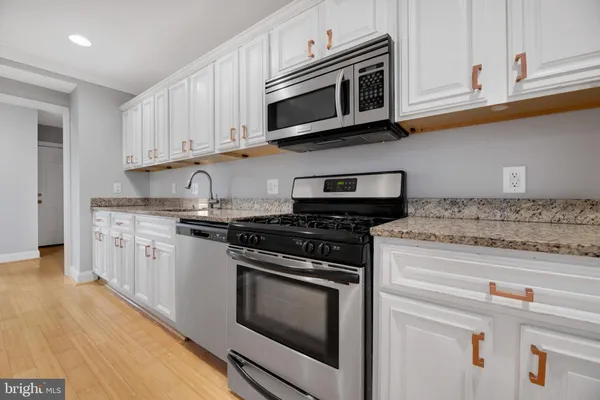 a kitchen with stainless steel appliances granite countertop white cabinets and a stove top oven