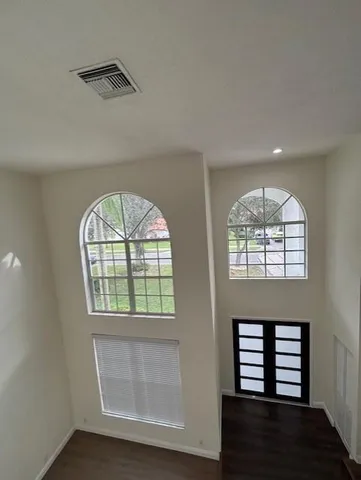 an empty room with wooden floor windows and entryway
