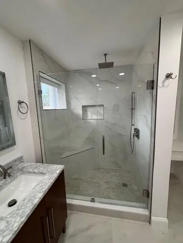 a bathroom with a granite countertop sink a mirror and shower