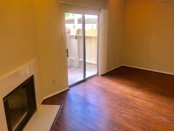 a view of an empty room with wooden floor and a fireplace