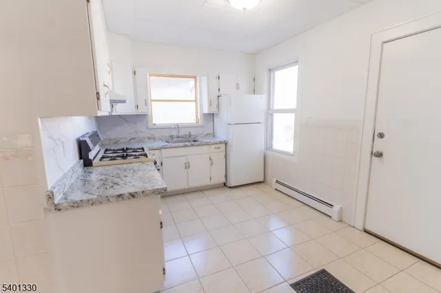 a kitchen with granite countertop a sink a stove a refrigerator and white cabinets