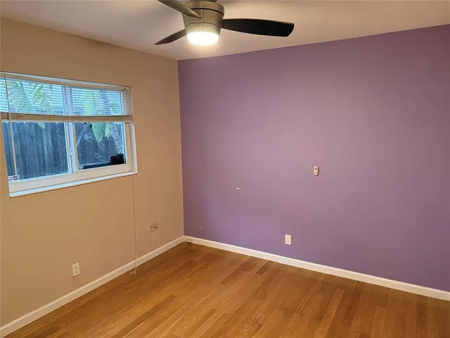 an empty room with a window and a ceiling fan