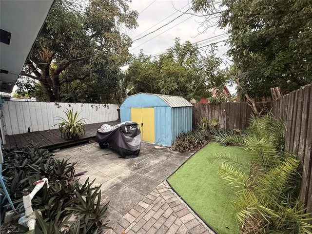 a view of a backyard with table and chairs potted plants and large tree