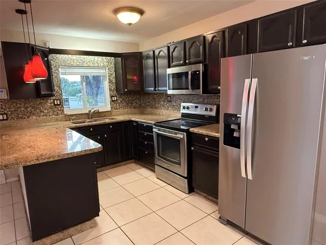 a kitchen with stainless steel appliances granite countertop a refrigerator and a sink