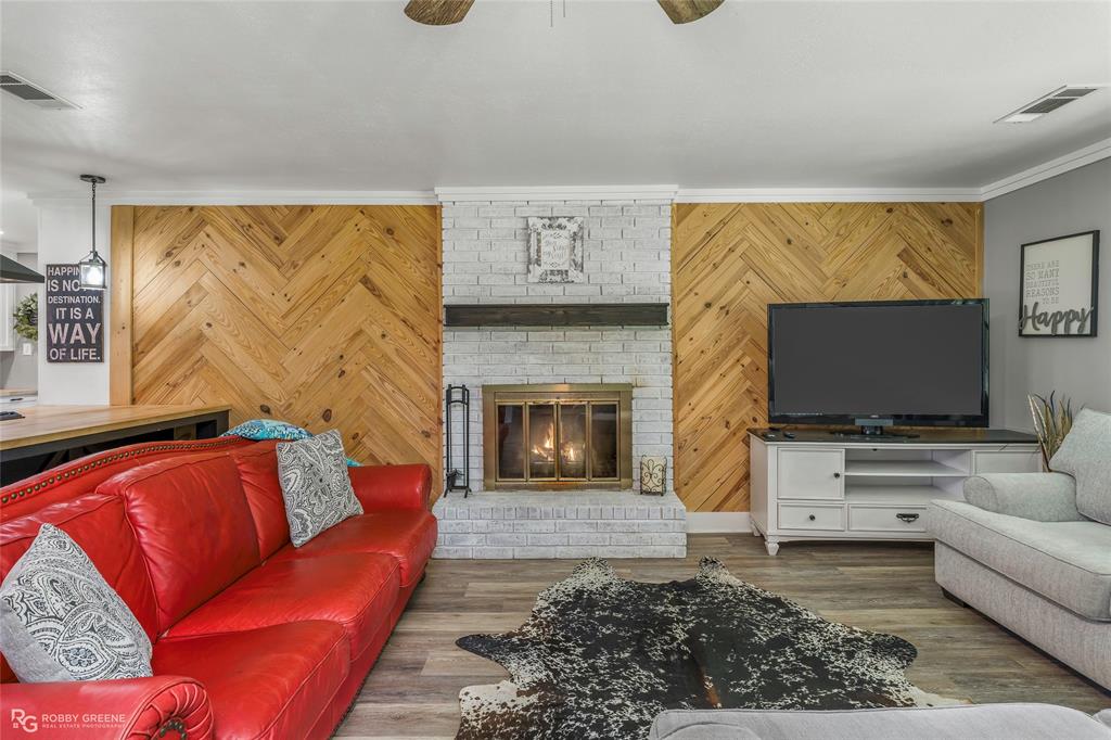 1426 Caney Lake Road Minden, LA 71055 - Photo 5 of 36 Herringbone wood-paneled accent wall with a whitewashed brick fireplace featuring a wood mantel