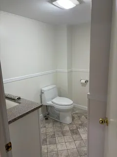 a bathroom with a granite countertop toilet and a sink