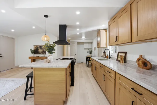 a kitchen with kitchen island granite countertop a sink a counter top space appliances and cabinets