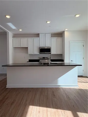a kitchen with granite countertop a stove a microwave and white cabinets