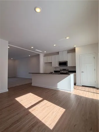 a kitchen with granite countertop a stove a microwave and white cabinets