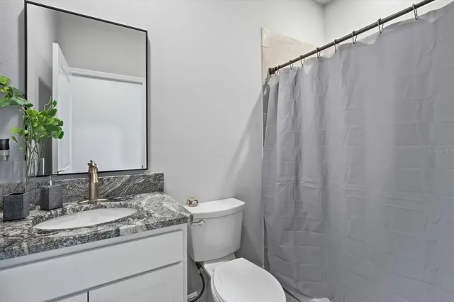 a bathroom with a granite countertop sink toilet and a mirror
