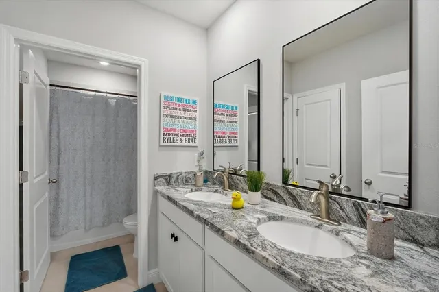 a bathroom with a granite countertop sink a mirror and shower