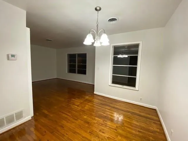 a view of an empty room with wooden floor and windows
