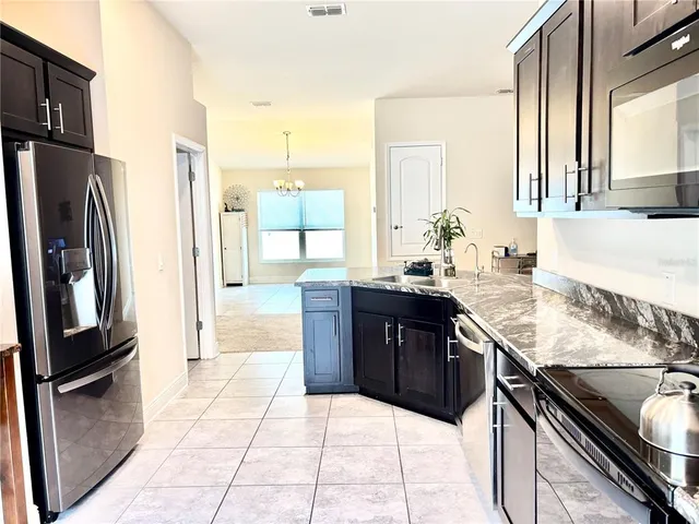 a kitchen with stainless steel appliances granite countertop a refrigerator a stove and a sink