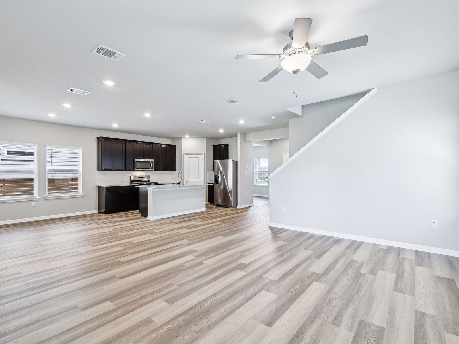 113 Maple Hedge Road Hutto, TX 78634 - Photo 7 of 20 an empty room with wooden floor and a kitchen