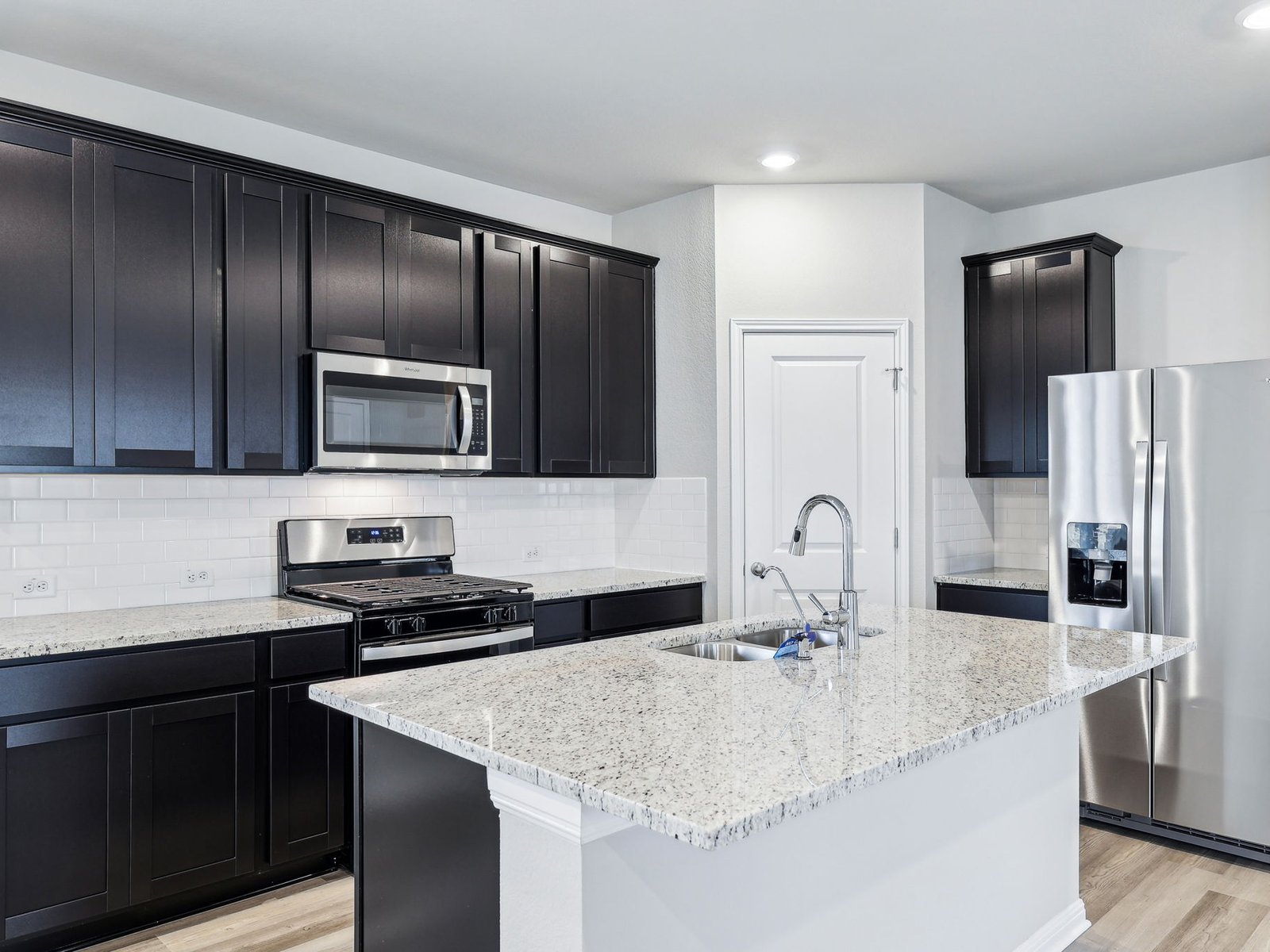 113 Maple Hedge Road Hutto, TX 78634 - Photo 9 of 20 a kitchen with granite countertop stainless steel appliances a sink stove refrigerator and cabinets