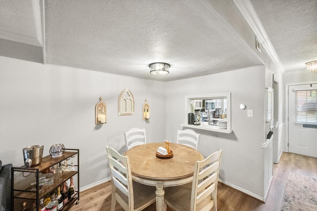 1379 Roaring Springs Road Fort Worth, TX 76114 - Photo 5 of 36 Dining area featuring wood-finish flooring, a pass-through window, and crown molding