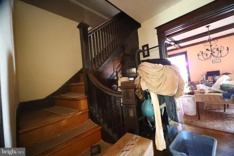 a living room with couches a dining table and a chandelier with wooden floor