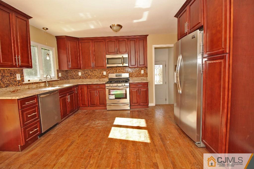 17 Brookside Road Edison, NJ 08817 - Photo 10 of 20 a kitchen with stainless steel appliances granite countertop a refrigerator a sink dishwasher a stove with wooden cabinets and floor
