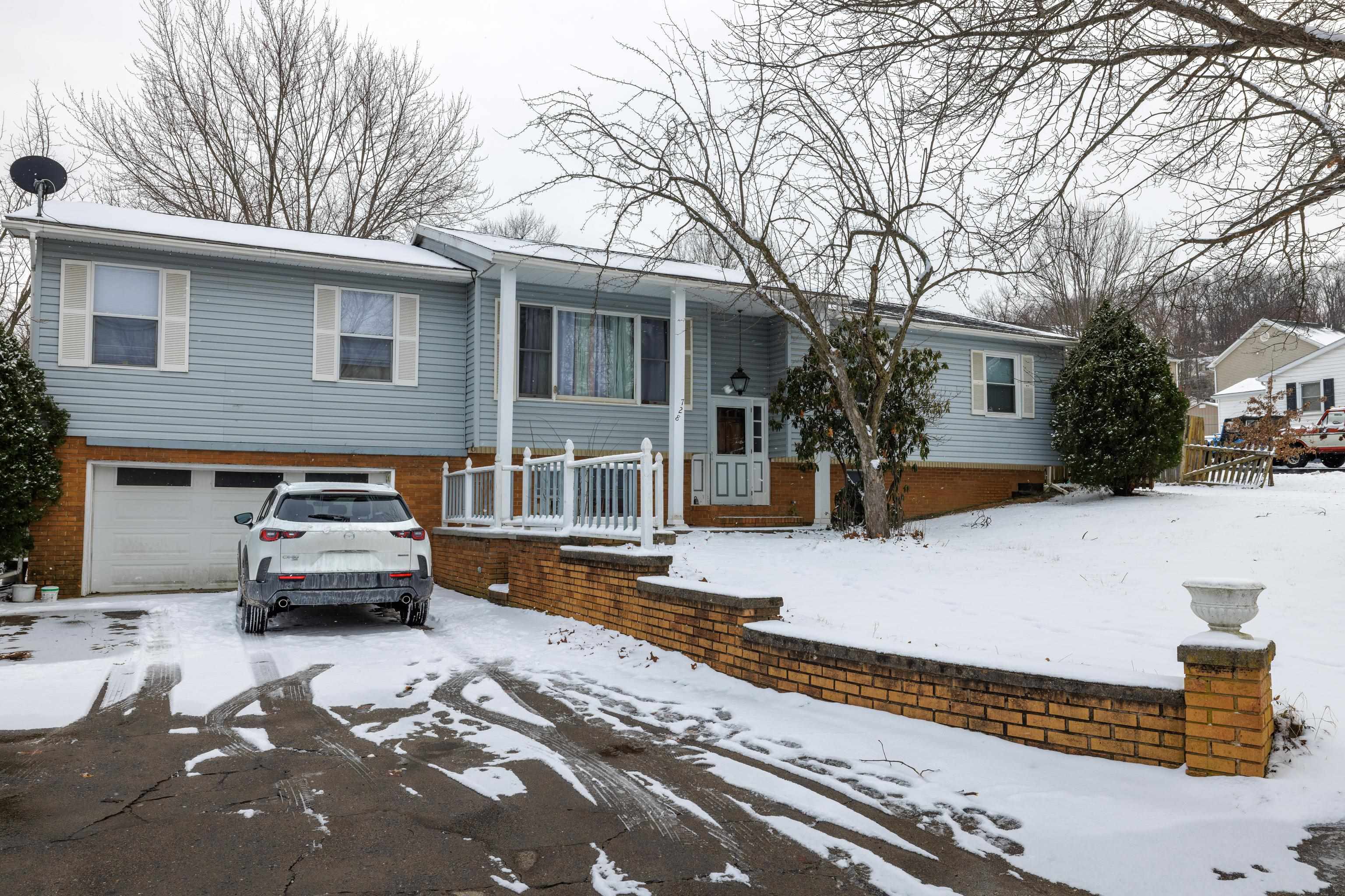 a front view of a house with cars parked on road
