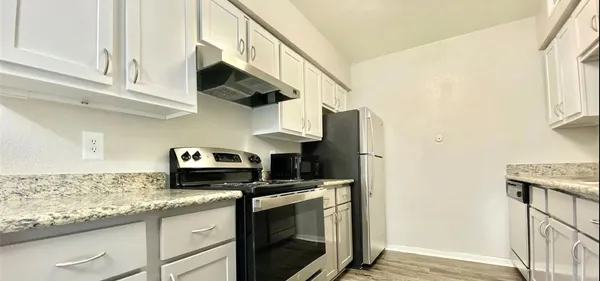 a kitchen with stainless steel appliances granite countertop a sink a stove and a wooden floors
