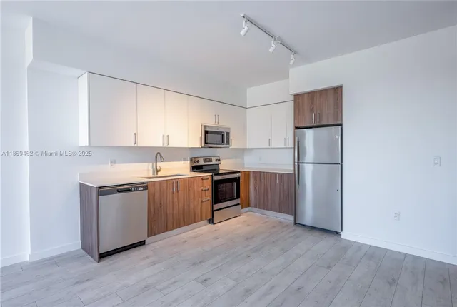 a kitchen with a refrigerator cabinets and wooden floor