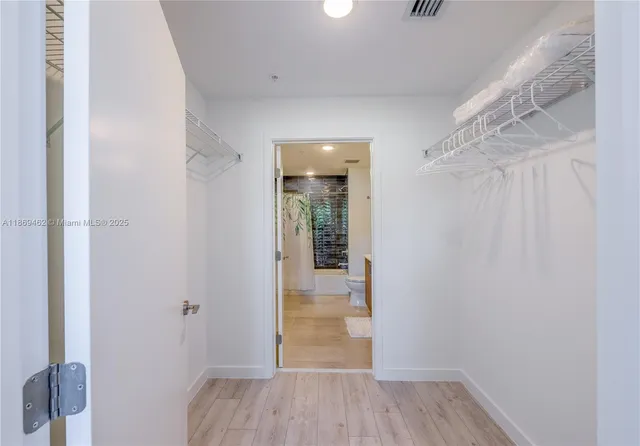a view of a hallway with wooden floor and closet area