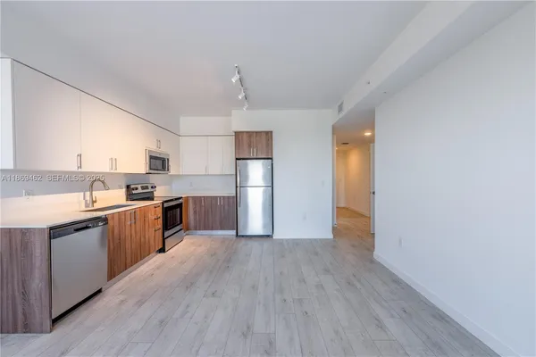 a large kitchen with a wooden floor and stainless steel appliances