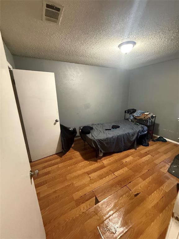 6036 Harrison Way Watauga, TX 76148 - Photo 15 of 39 Bedroom with a textured ceiling and wood finished floors