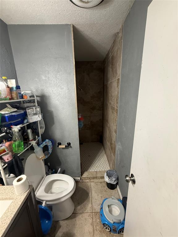 6036 Harrison Way Watauga, TX 76148 - Photo 30 of 39 Full bathroom with a textured ceiling, vanity, a shower stall, and light tile patterned flooring