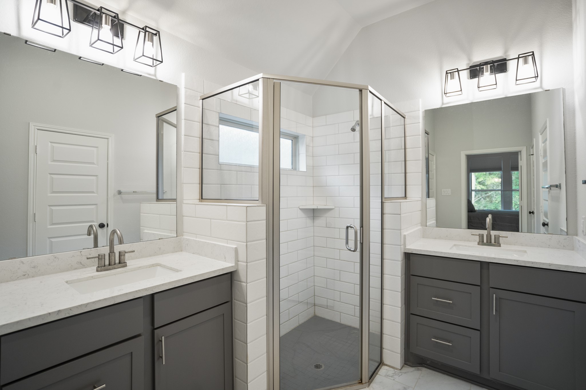 334 Topper Pines Drive Montgomery, TX 77316 - Photo 21 of 49 Closer in, the ensuite bath continues the farmhouse-inspired feel with white subway tile, coordinating light fixtures, and an oversized shower between the dual vanities. Cabinet storage on both sides keeps daily essentials tucked away but easy to reach.