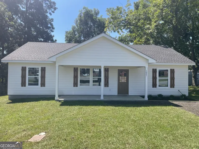a view of a yard in front of a house with large windows