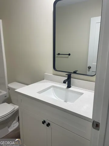 a bathroom with a sink toilet and mirror