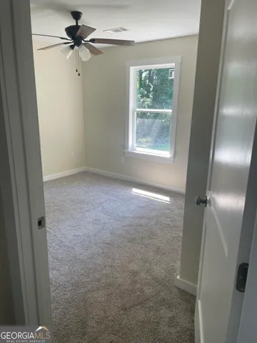 an empty room with windows and fan