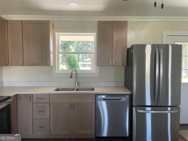 a kitchen with stainless steel appliances granite countertop a refrigerator sink and white cabinets