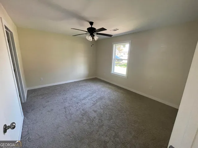 an empty room with windows and fan