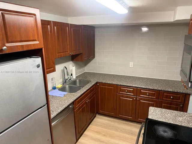 a kitchen with granite countertop wood cabinets a sink and dishwasher