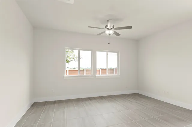 a view of an empty room with kitchen and window